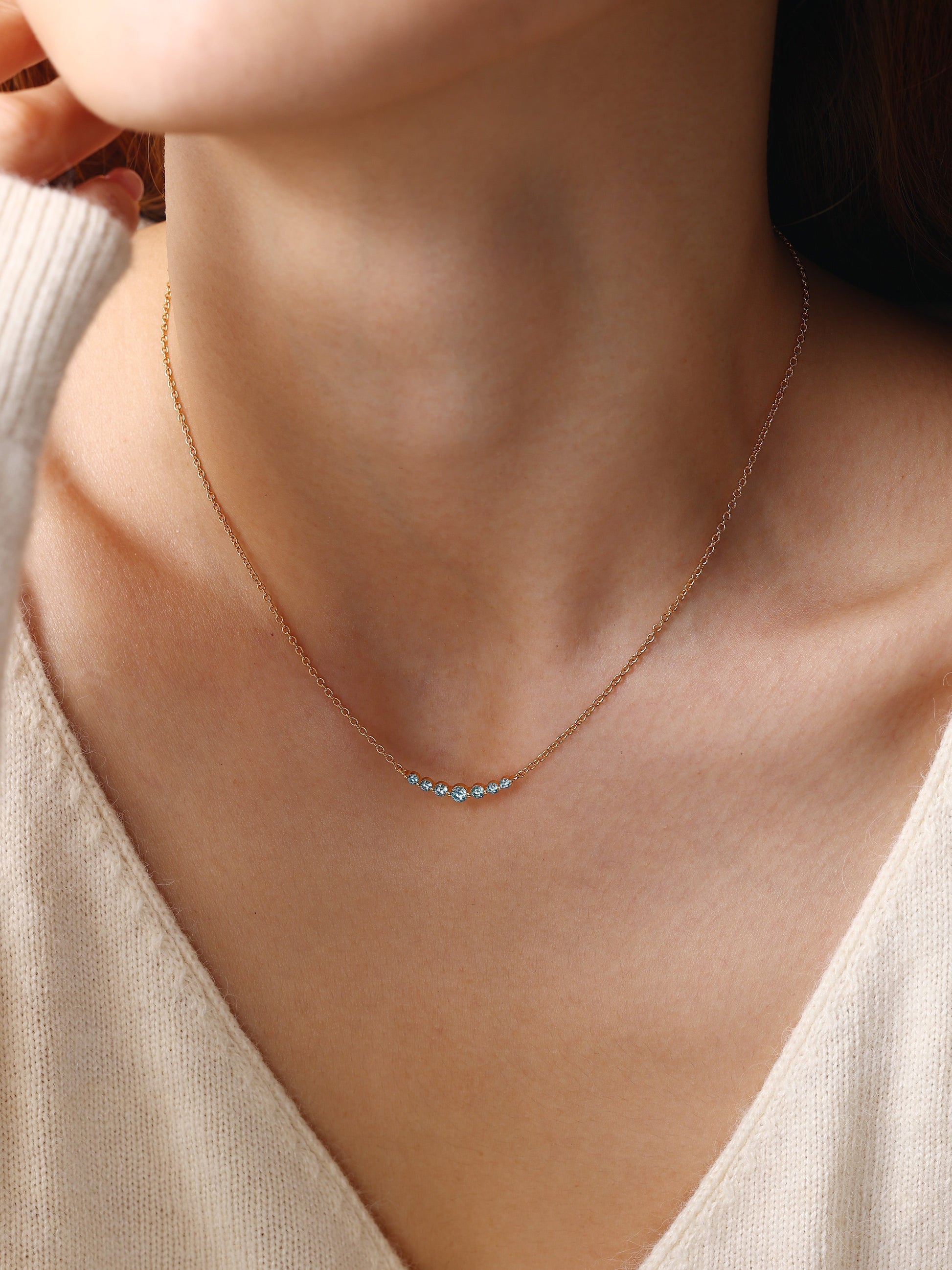 Birthstone Arc Necklace with March birthstone, worn on a model