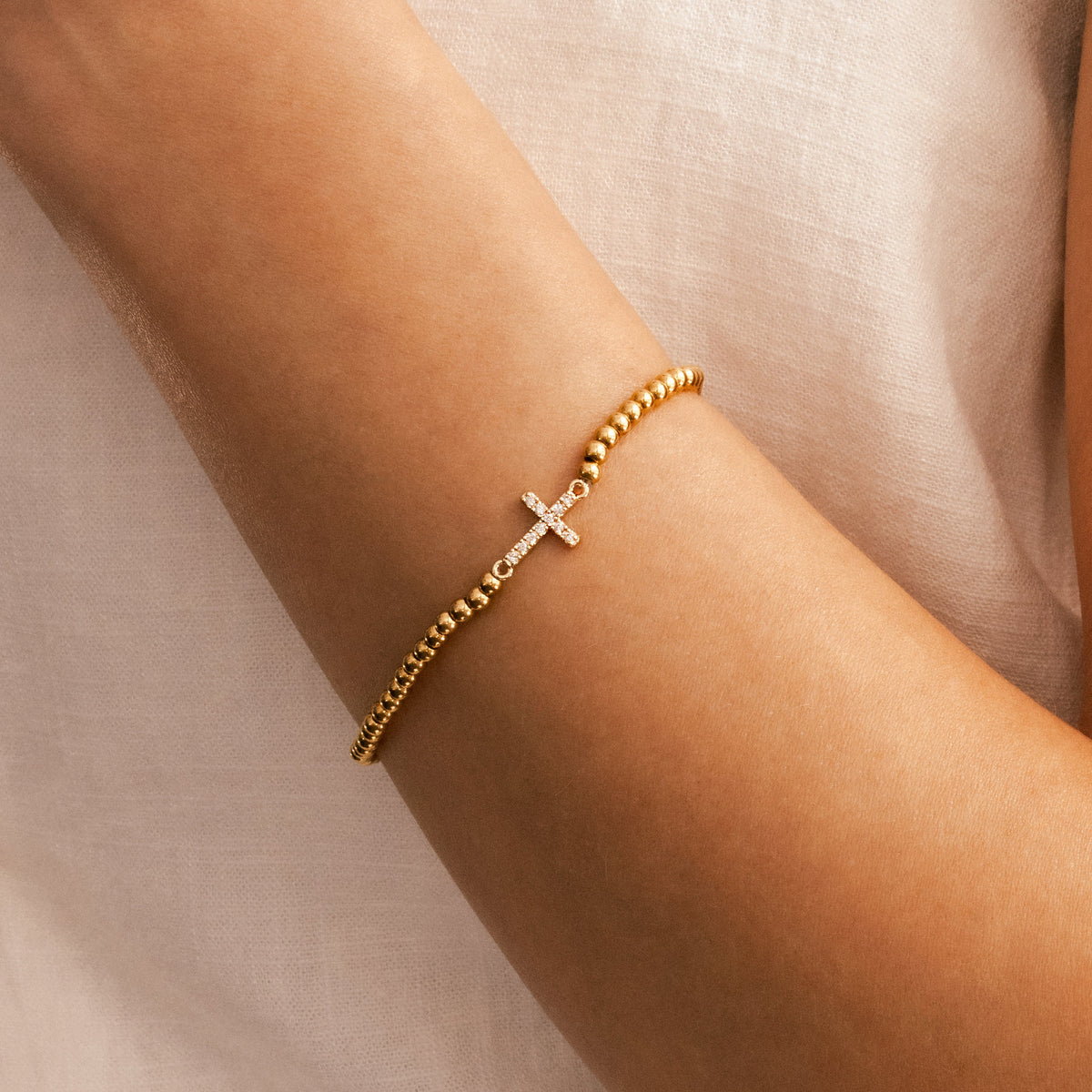 Gold Beaded Cross Stretch Bracelet, worn on a model