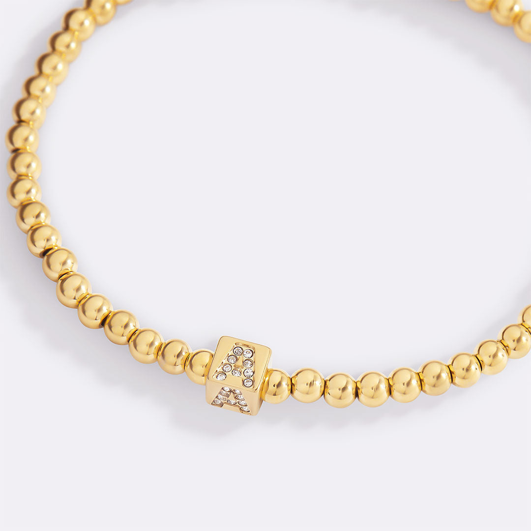 Bracciale con iniziale a blocchi e perline dorate